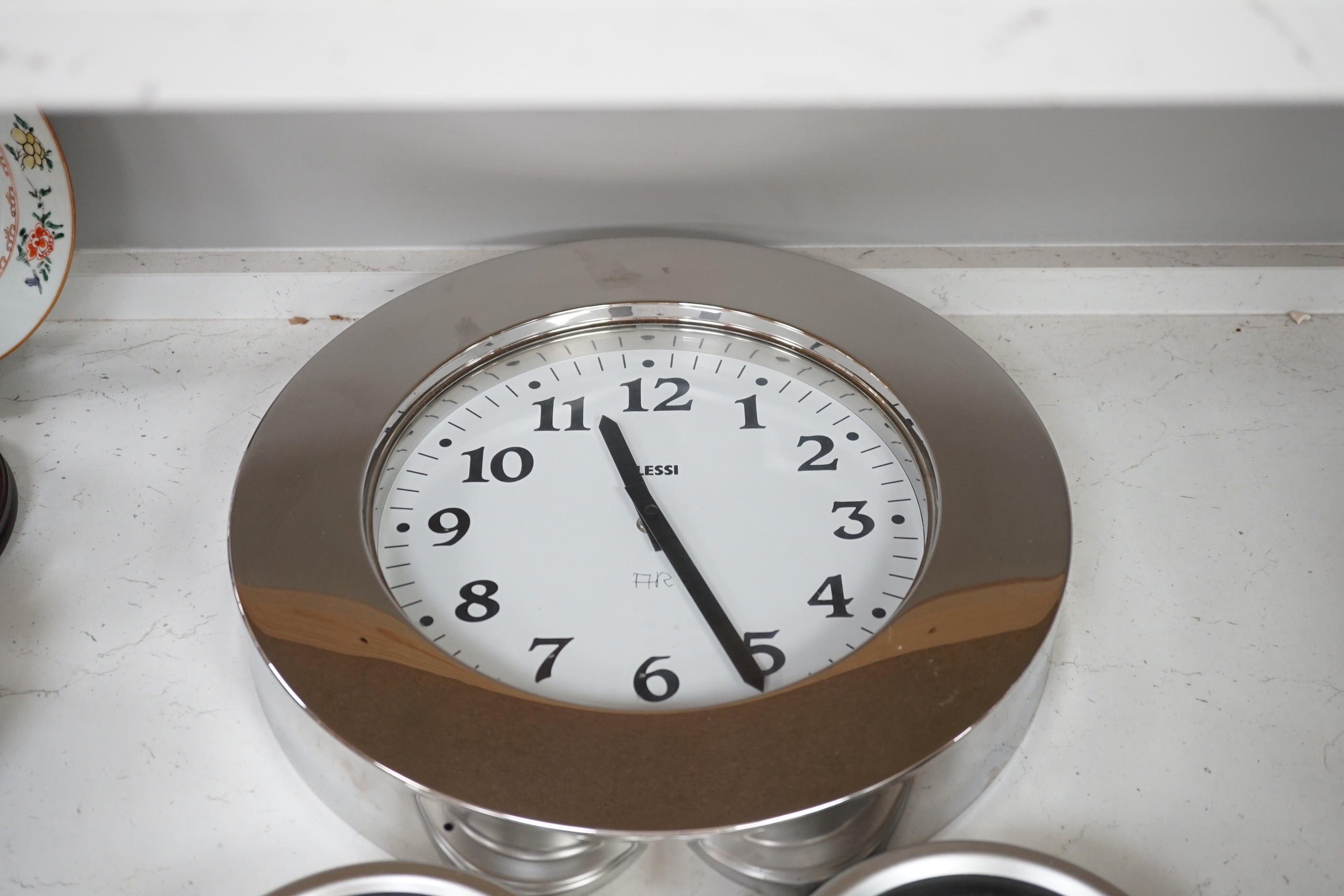 An Alessi wall clock and three similar smaller wall dials